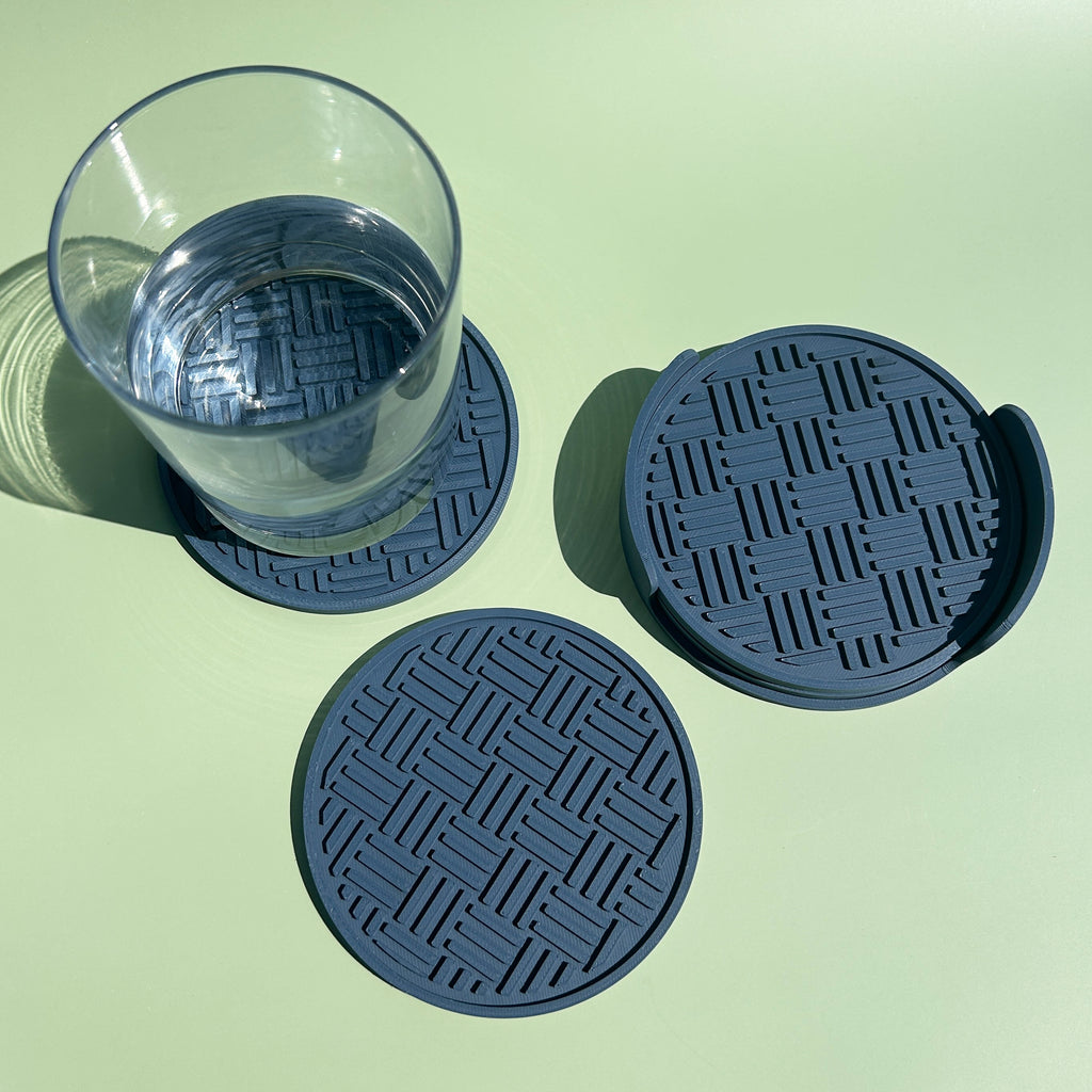 a glass of water on a green background, with two coasters placed next to it.