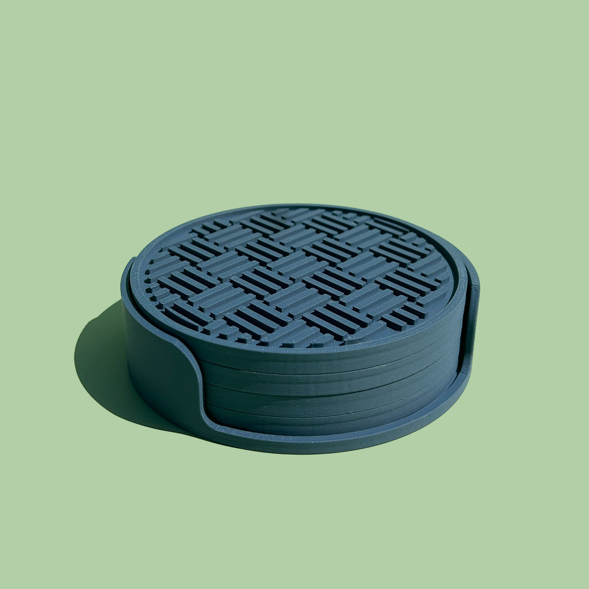 A blue coaster with a geometric pattern on it, sitting on a green background.