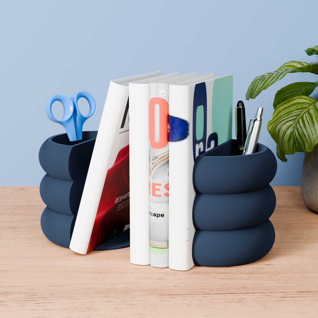 A wooden desk with a blue cylindrical container holding a pair of scissors, a book, and a pen, along with a plant in the background.